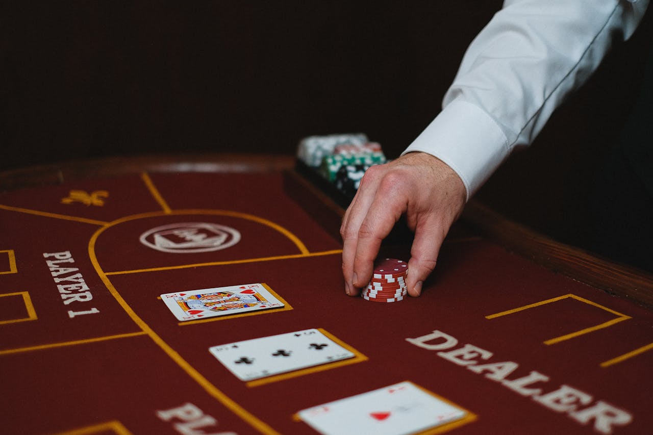 Close-up of a dealer handling poker chips on a casino table, showcasing cards and layout.