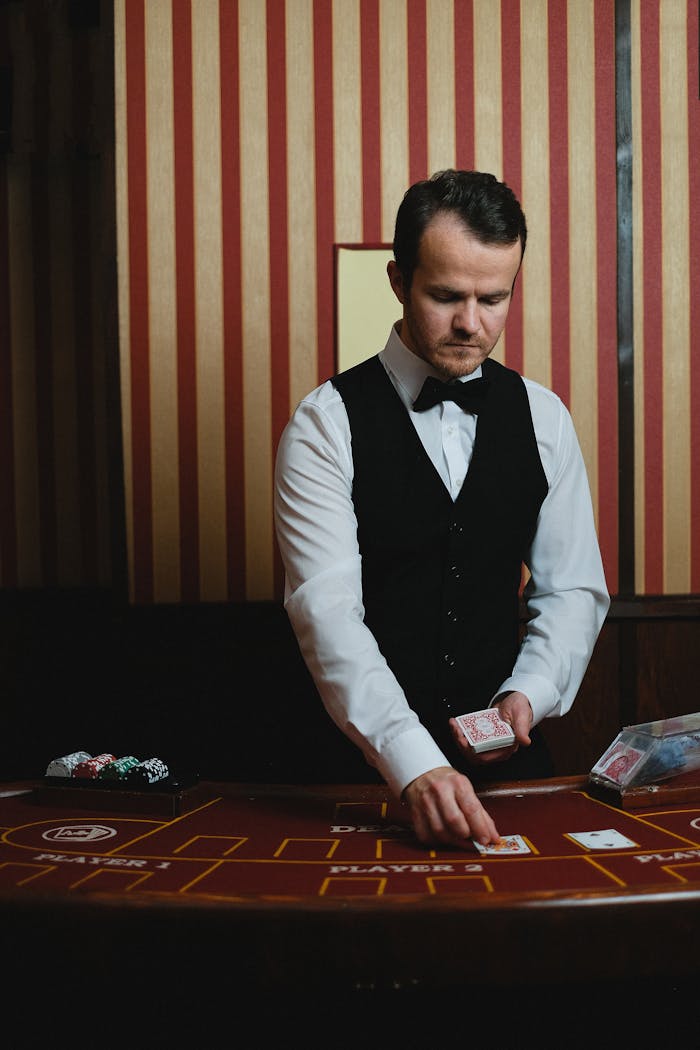 Elegant croupier in a casino dealing cards at a poker table under dim lighting indoors.
