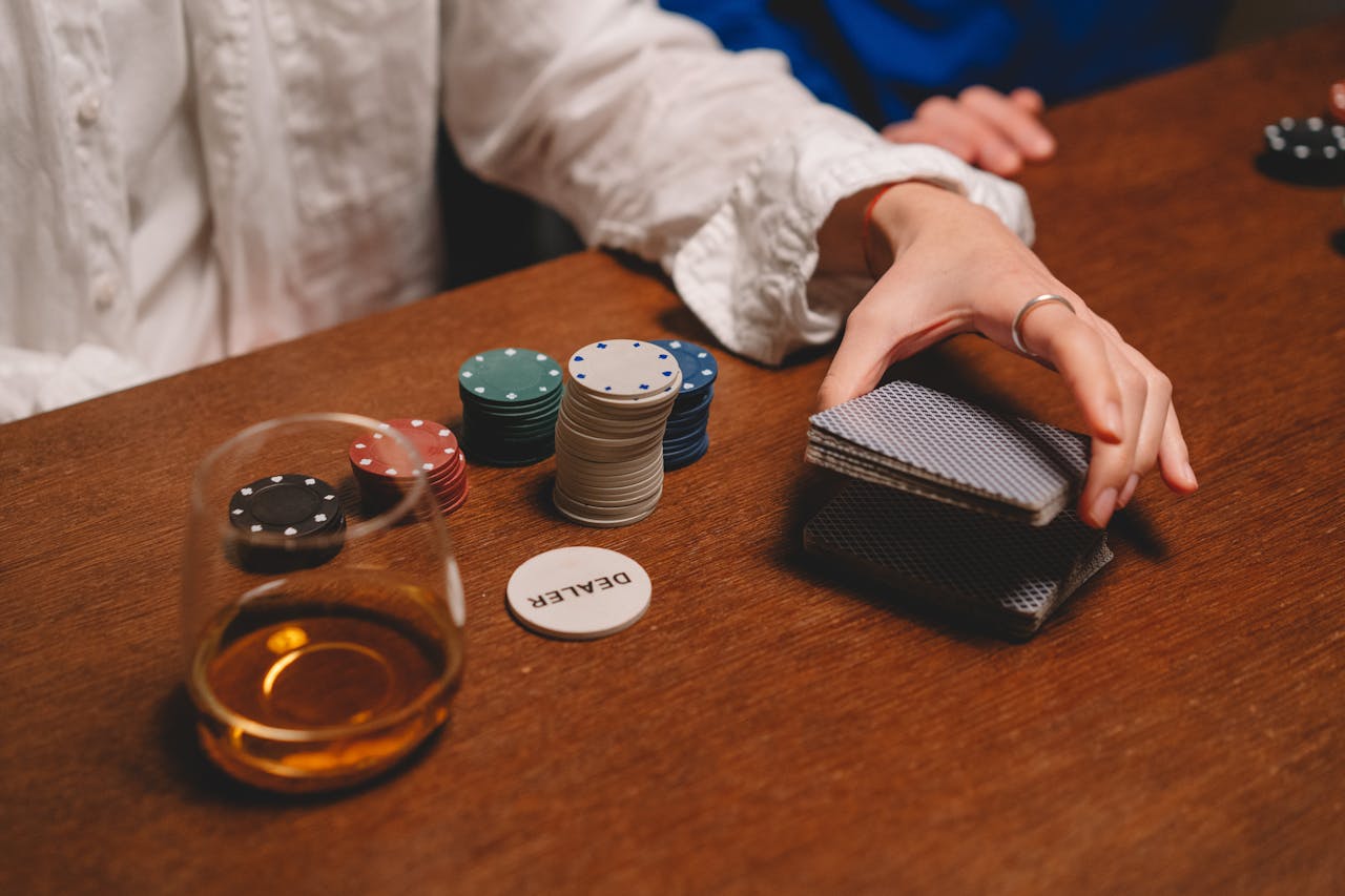 A cozy indoor poker game featuring chips, cards, and a glass of whiskey on a wooden table.